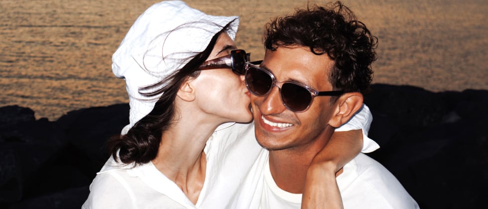 A woman is kissing a man on the cheek. They look very happy.