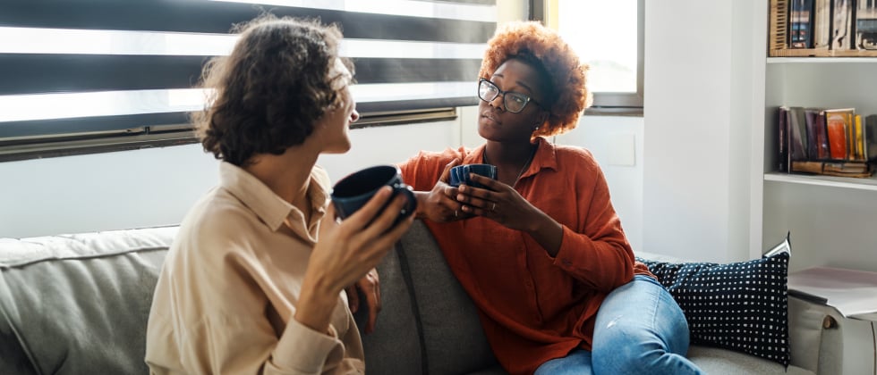 Two women sitting on a couch, chatting about unrequited love