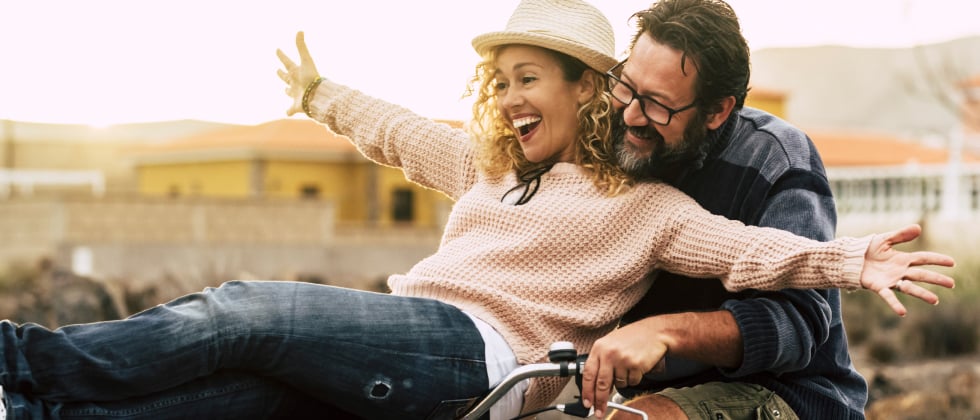 An older woman and younger man laughing on a bike.