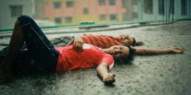 A couple laying on the ground in the rain laughing