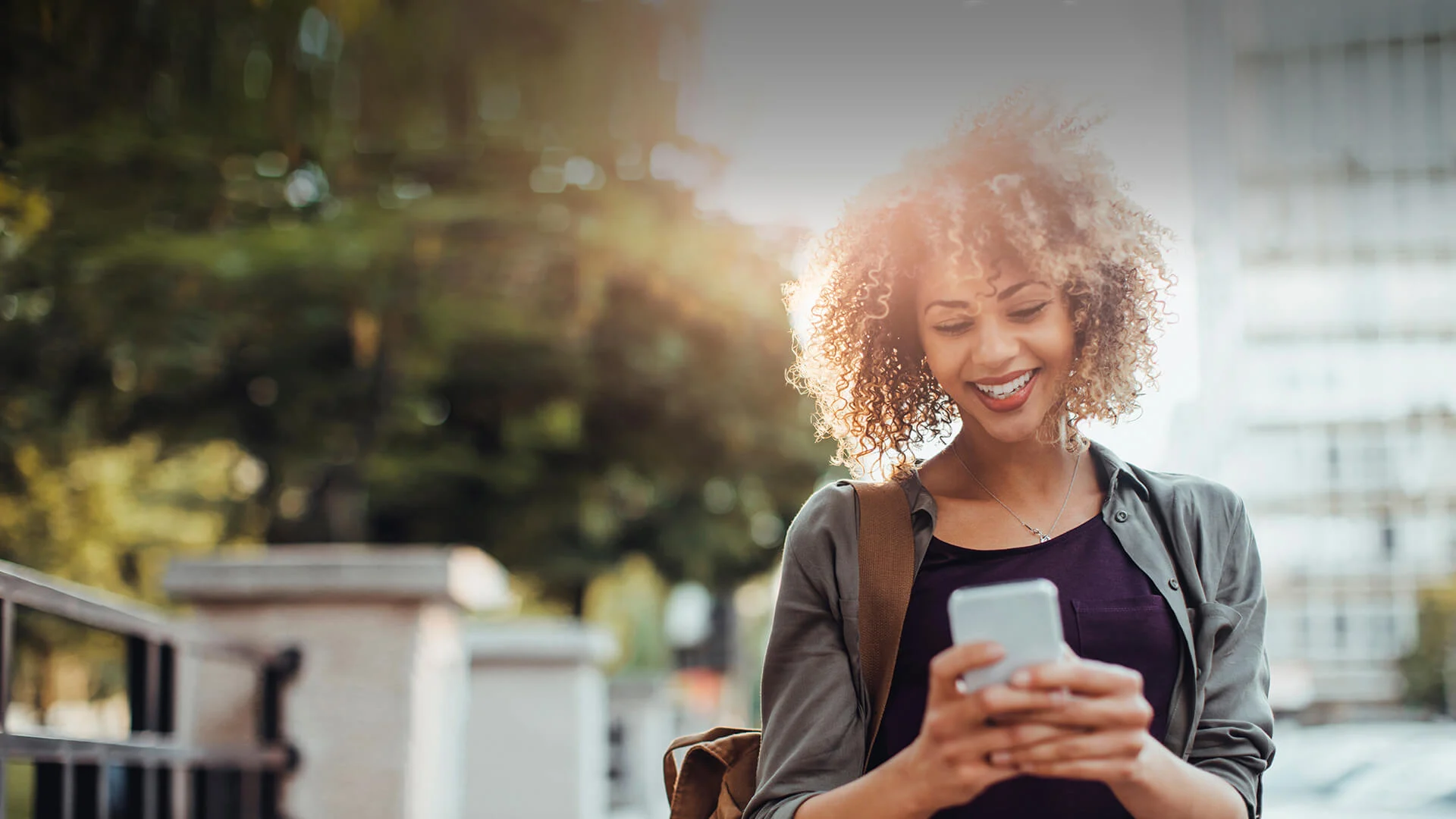 Black single woman smiles in her smartphone while dating online