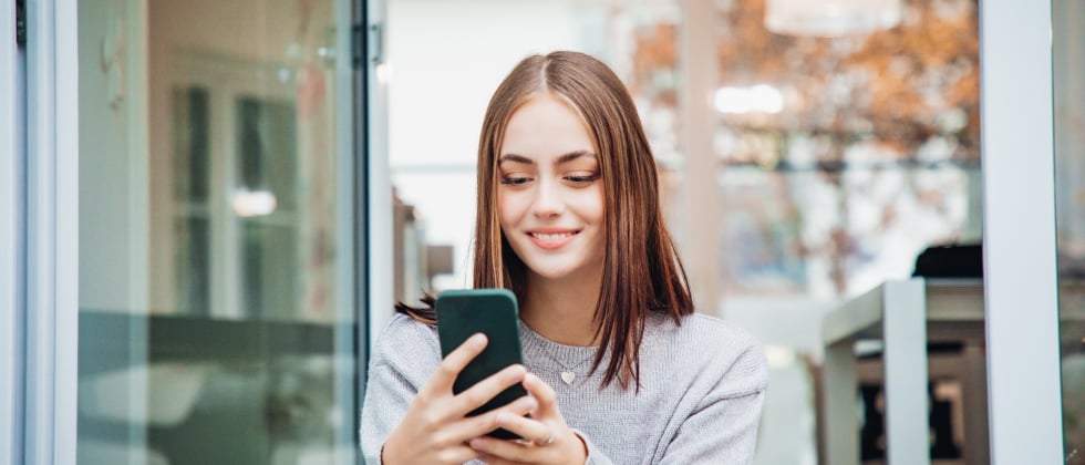 A woman lokking at her phone, thinking about "should I call him?"