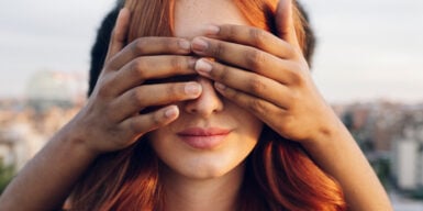 A man covers a womans eyes, telling her words of affirmation