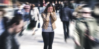 A woman covering her face with her hands in a crowd of people